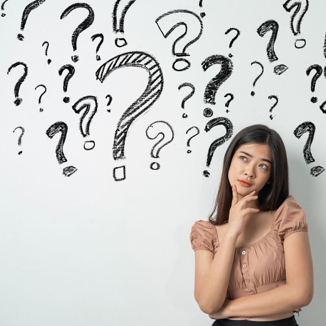 woman contemplating in front of a wall of question marks