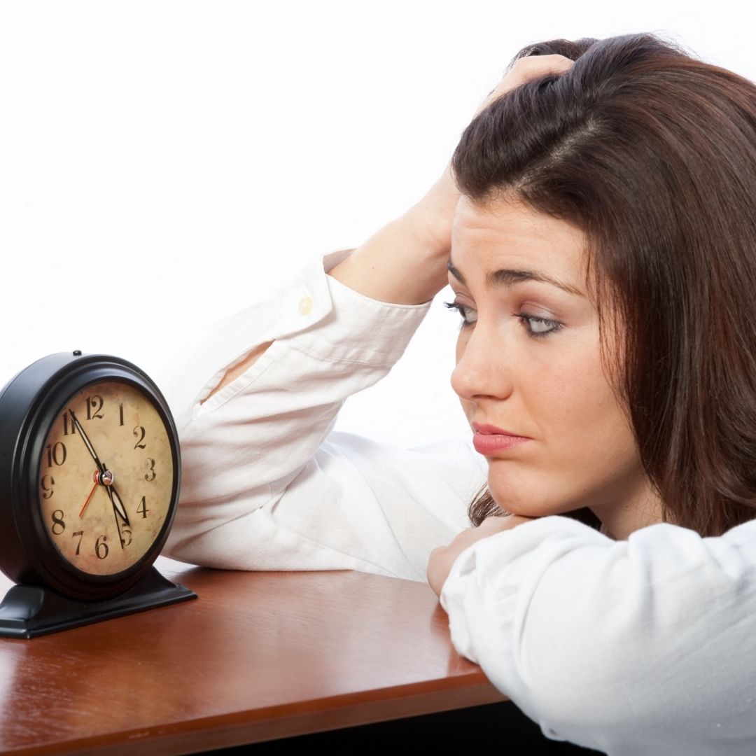 woman impatiently stares at a clock