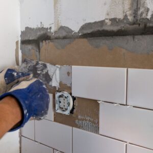 hands repairing tiled wall